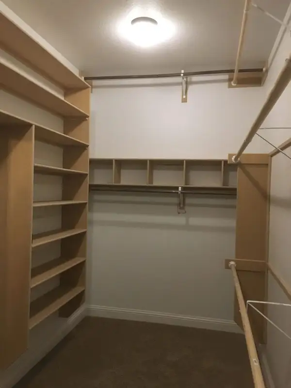 Walk-in closet with unpainted built-in shelves, cubbies and wood hanging rods