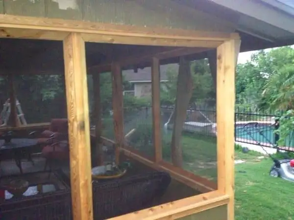 Screened porch framing seen from inside, with outdoor seating and a pool beyond the lawn
