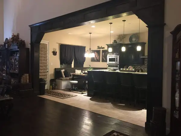 Kitchen opening framed by a dark-stained paneled wood surround with a decorative center medallion