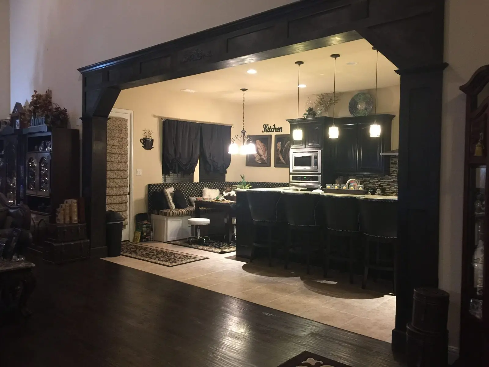 Kitchen opening framed by a dark-stained paneled wood surround with a decorative center medallion