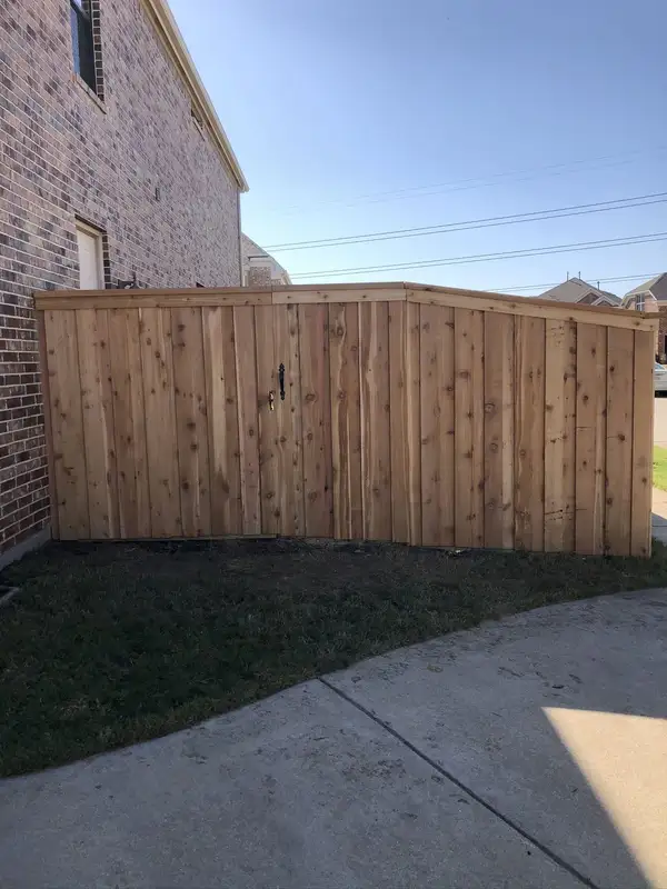 Cedar privacy fence and gate with an angled top rail along the side of a brick home