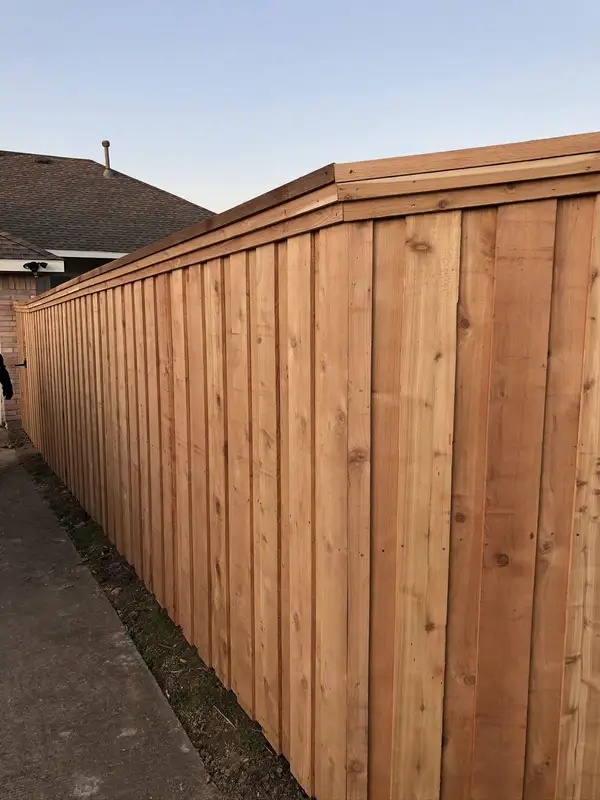 Long cedar board-on-board privacy fence with a capped top running along a side yard