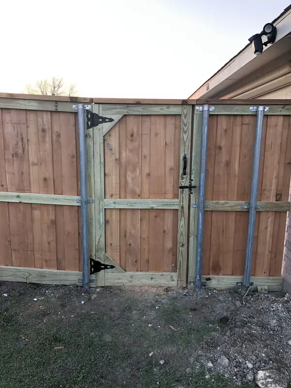 Cedar privacy fence gate with black strap hinges, steel posts and diagonal cable bracing
