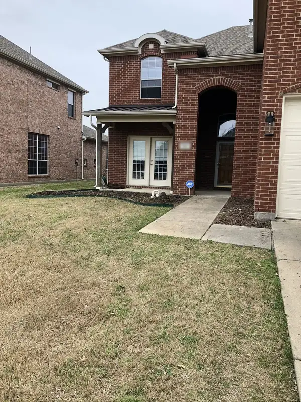 Front of a brick home with a curved steel-edged mulch bed and a patchy dormant lawn