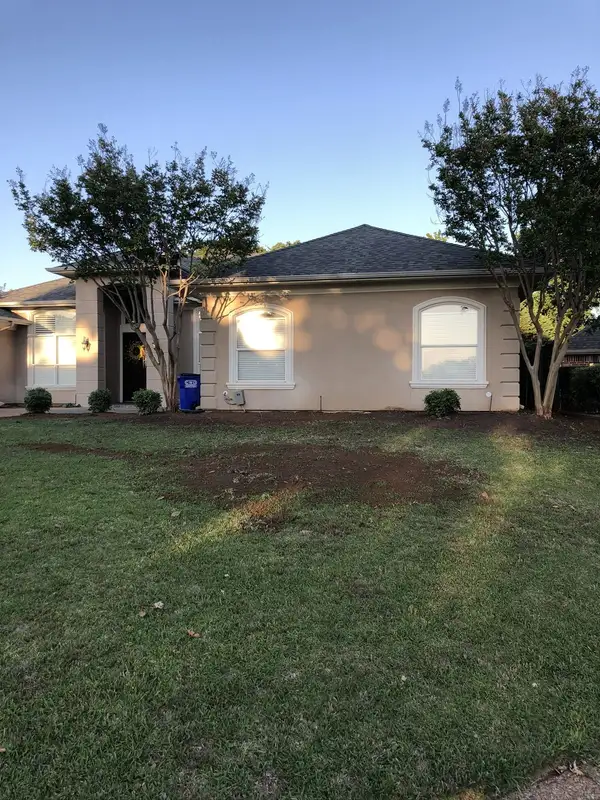 Front yard of a stucco home with freshly turned soil in the lawn and along the foundation