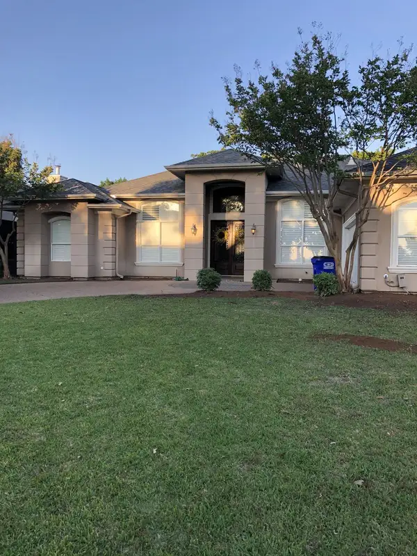 Stucco home front with a green lawn and a strip of freshly raked soil along the foundation