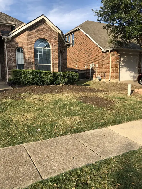 Brick home with freshly worked soil beside trimmed shrubs and a turned soil patch in a dry lawn